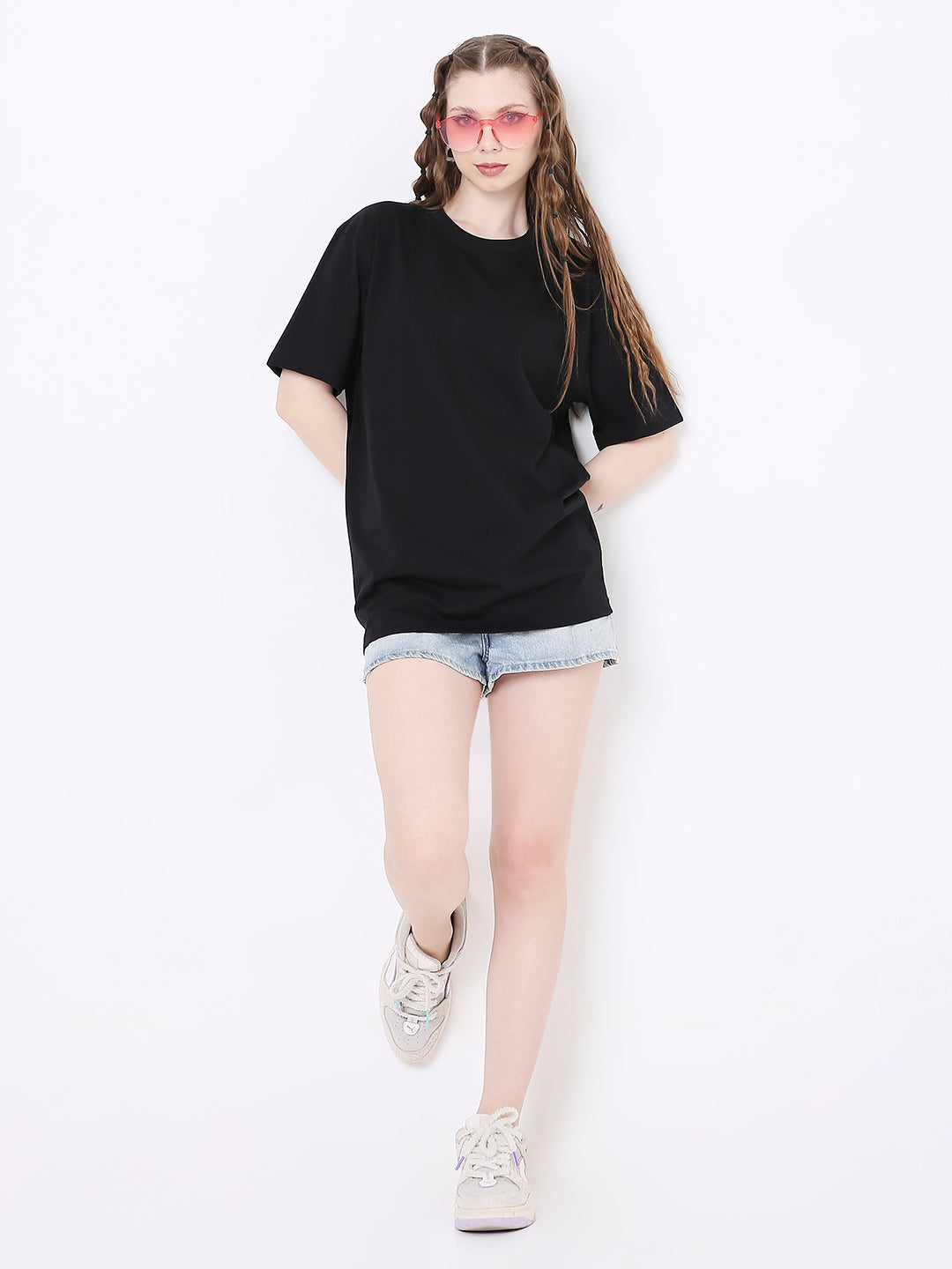Black relaxed fit t-shirt paired with light denim shorts and white sneakers, worn by a model.