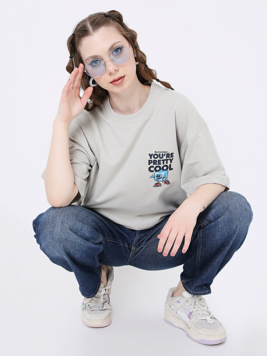 Oversize light gray t-shirt with black blue skipping stone print and text, paired with dark jeans and sneakers.