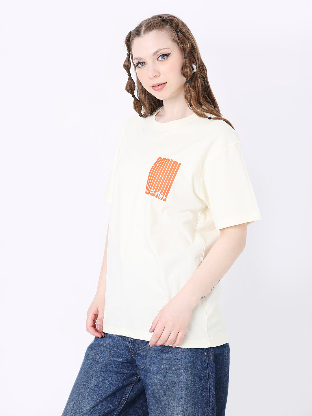 Off-white relaxed fit t-shirt with small orange graphic on chest, paired with blue jeans.