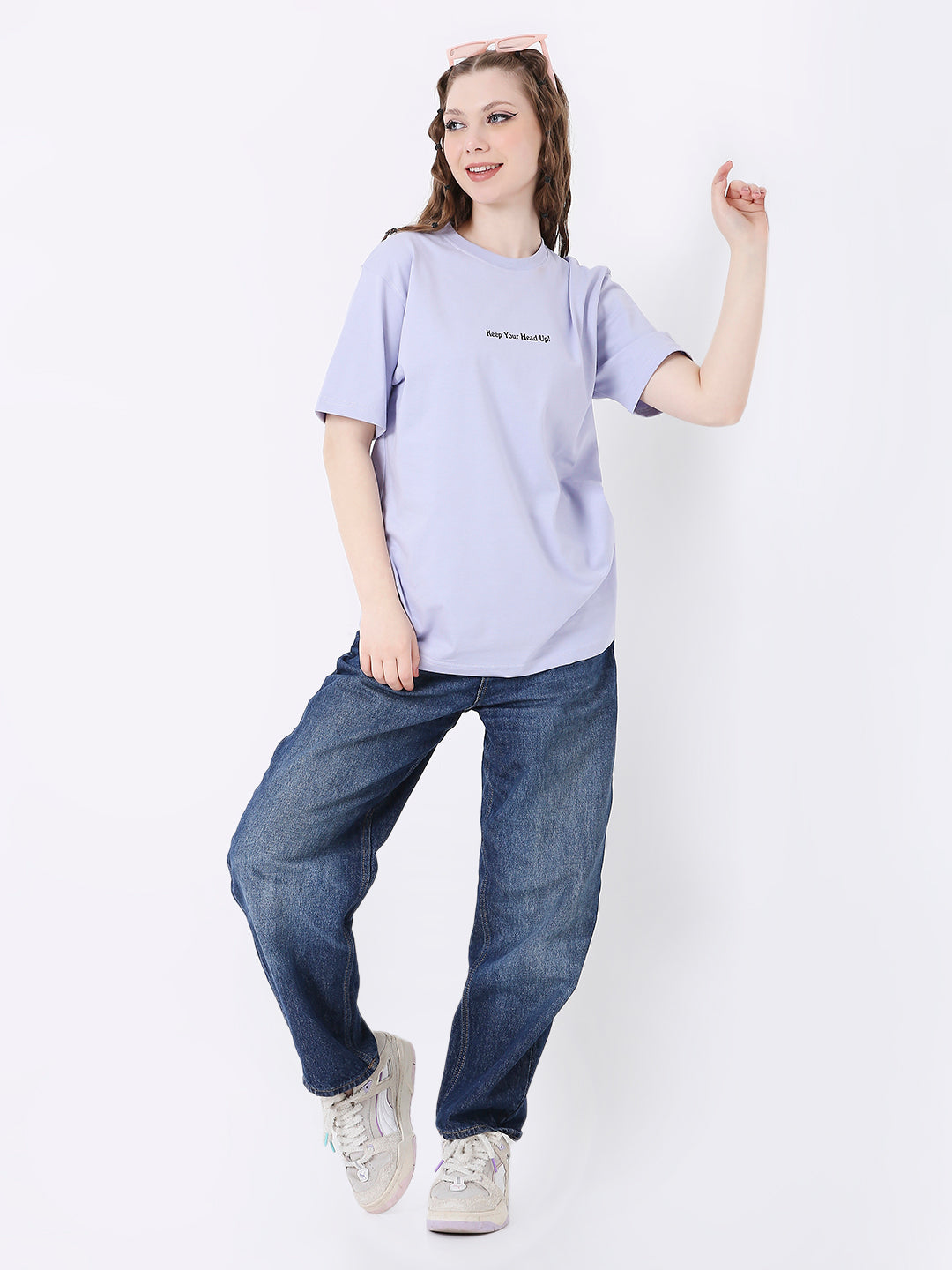 Lavender relaxed fit t-shirt with small black text print, paired with loose blue jeans and white sneakers.