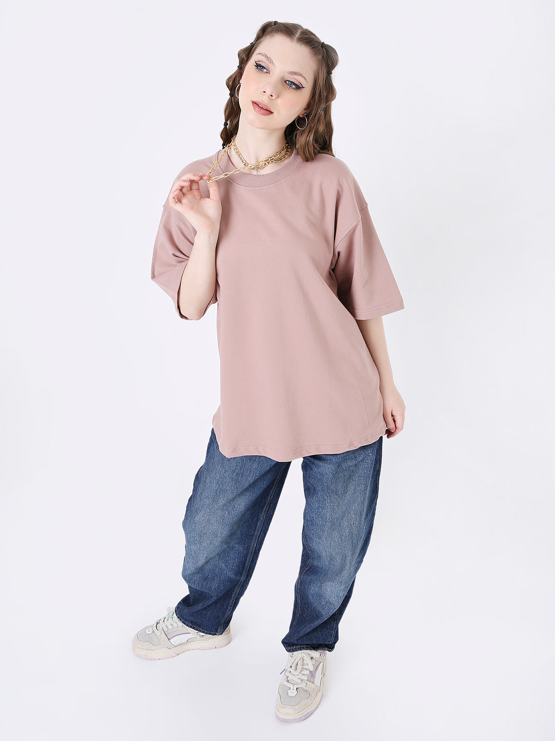 Oversize onion pink solid t-shirt with short sleeves paired with loose blue jeans and white sneakers.