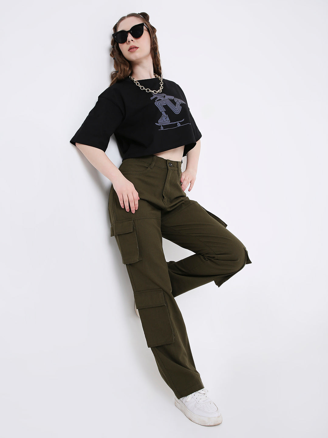 A female model wearing black cropped tank top with olive green 8-pocket cargo pants
