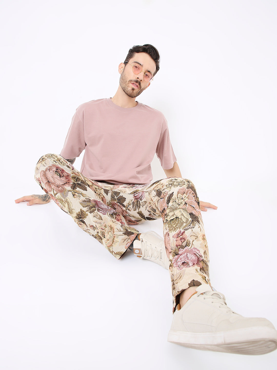 Oversize onion pink solid t-shirt paired with beige floral print pants and white sneakers.