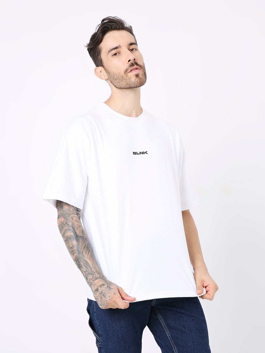 Oversize white cotton t-shirt with small black printed text on chest, worn with dark jeans.