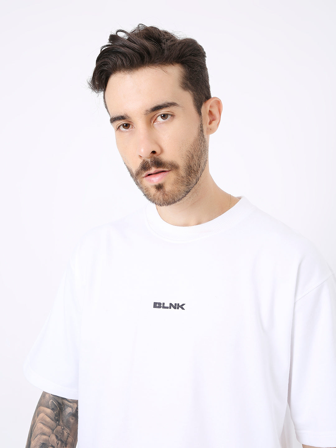 White oversized T-shirt with small black "BLANK" text printed on chest, worn by male model.