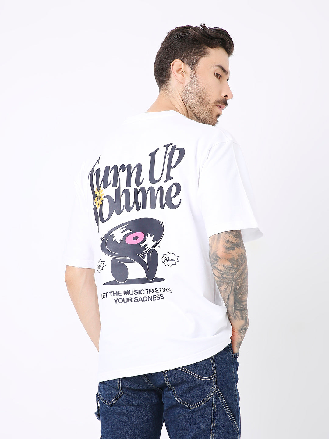 White oversized t-shirt with bold black and pink "Turn Up Volume" graphic and vinyl record print on back.