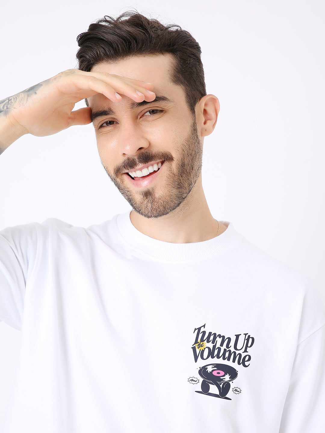 White oversized t-shirt with black and colorful "Turn Up Volume" text and graphic on chest.