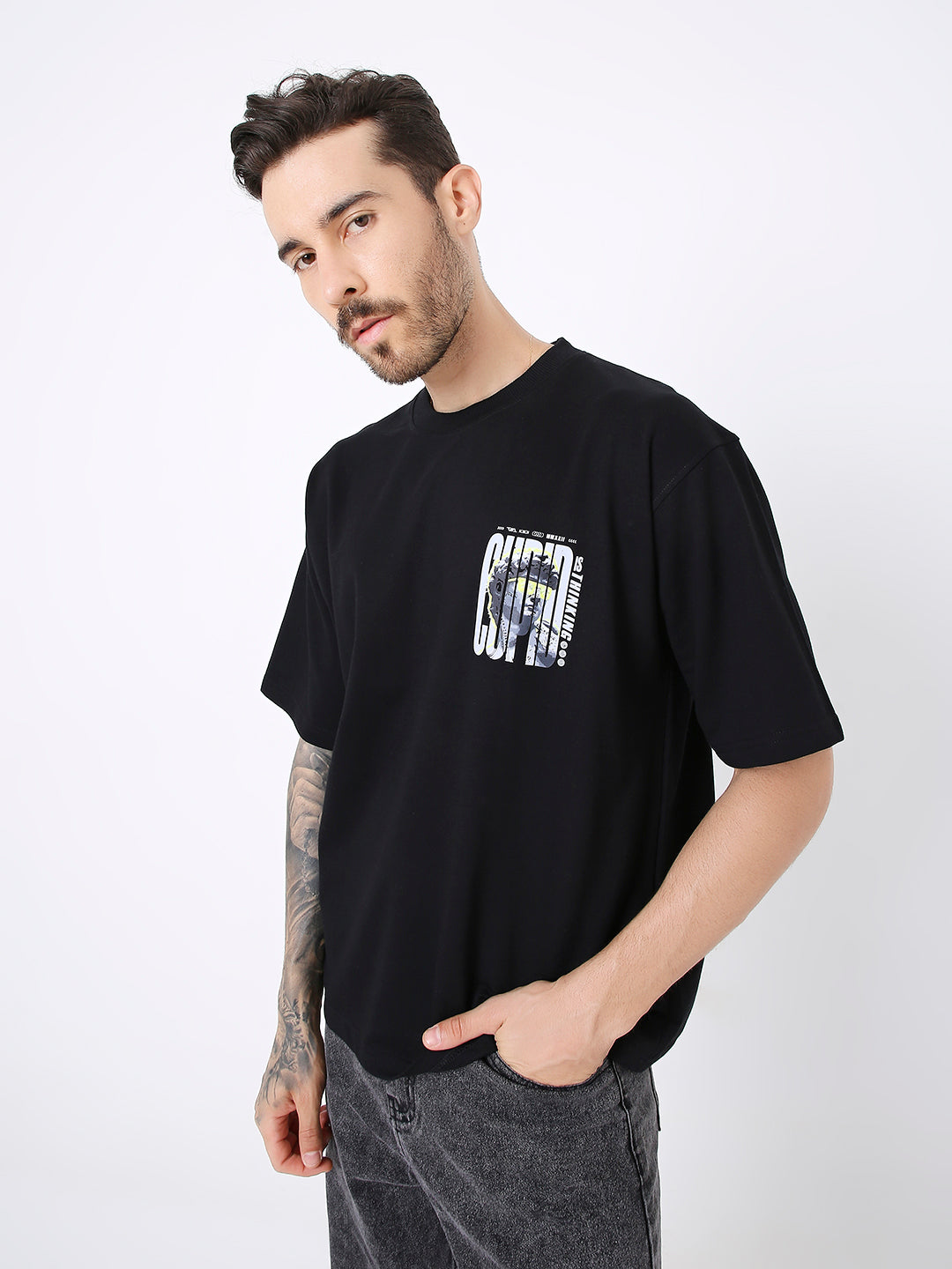 Oversize black t-shirt with small white and yellow printed design on left chest, relaxed fit.