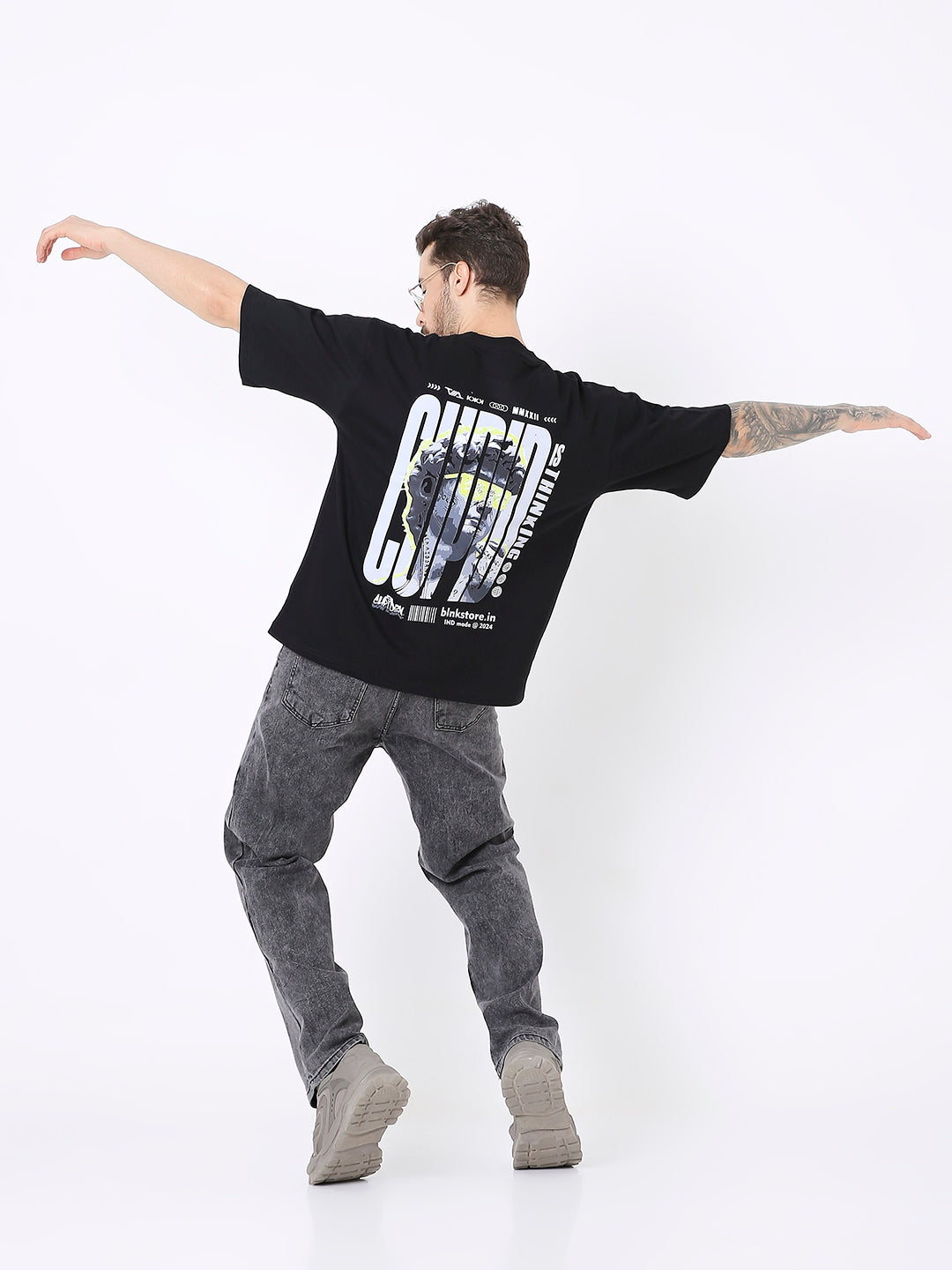 Oversize black T-shirt with large white and yellow graphic print on back, paired with gray jeans and boots.