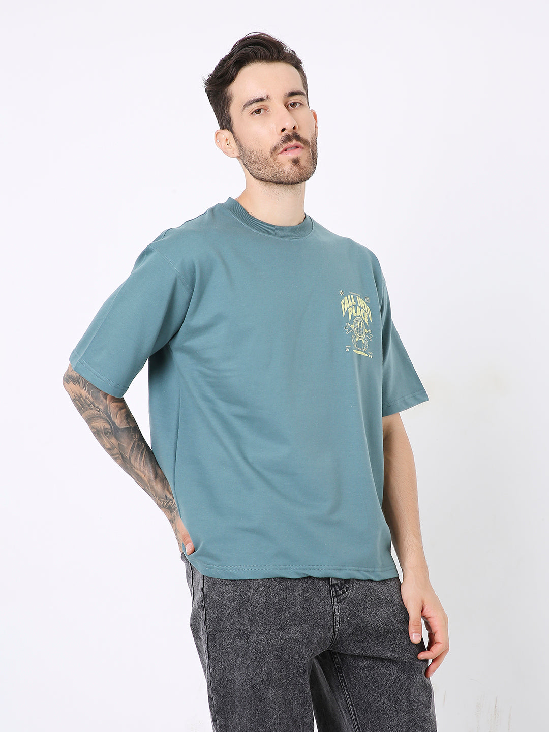 Oversize sapphire blue t-shirt with yellow graphic print on chest, paired with dark gray jeans.