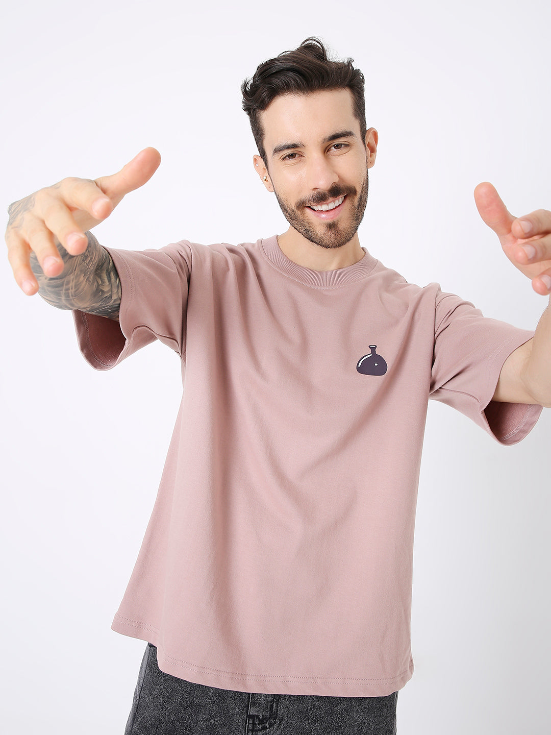 Oversize onion pink t-shirt with small black graphic on left chest, worn by smiling man.