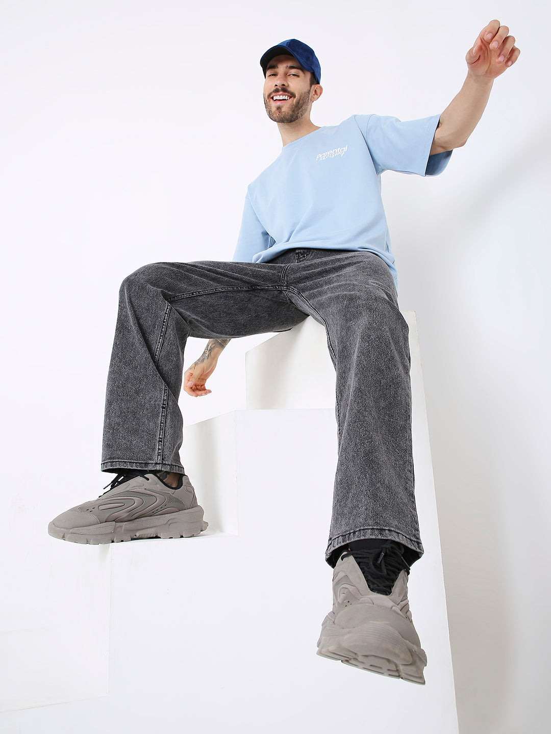 Light blue oversized T-shirt with long sleeves, worn with dark gray jeans and gray sneakers.