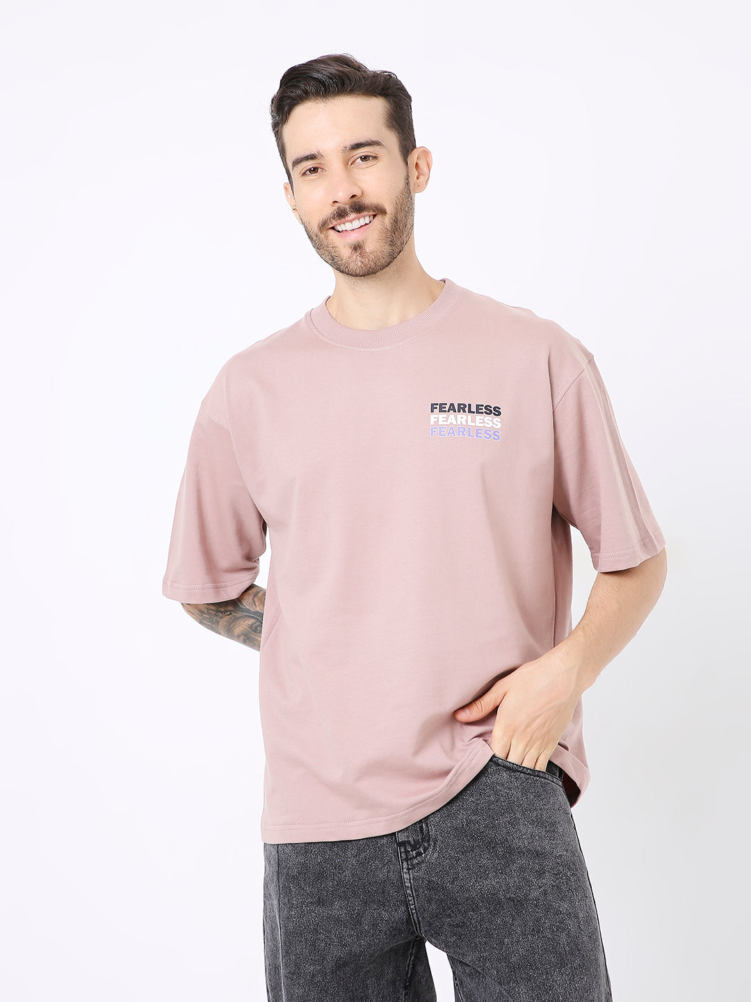 Oversize onion pink t-shirt with small black text print on chest, worn with dark denim jeans.