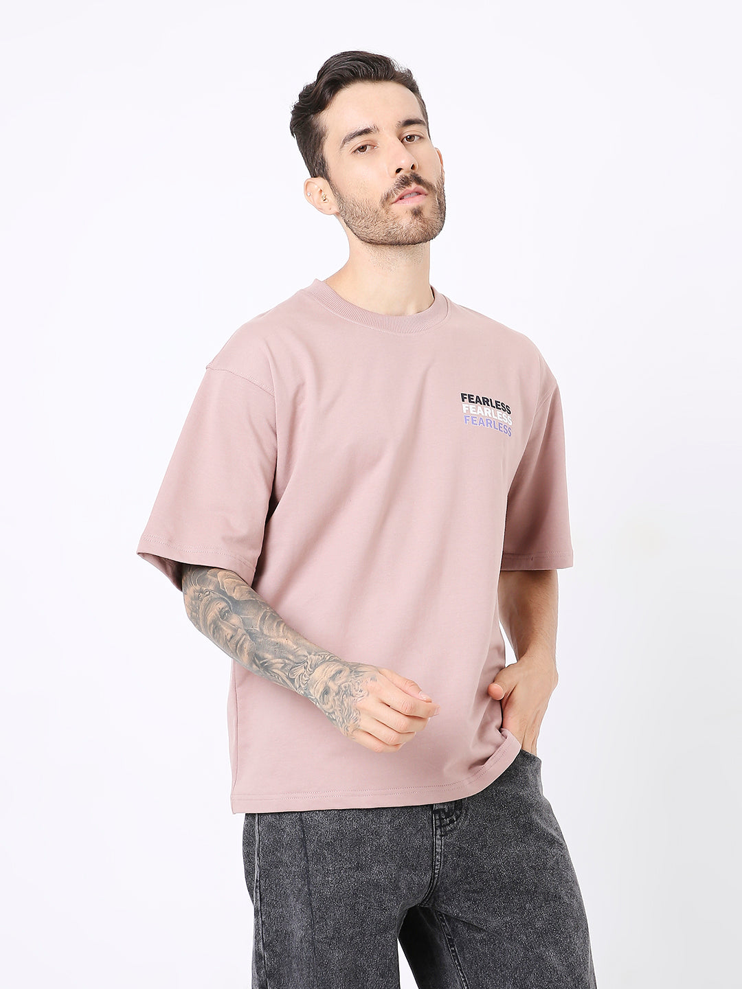 Oversize onion pink t-shirt with small black printed text on left chest, worn with black jeans.