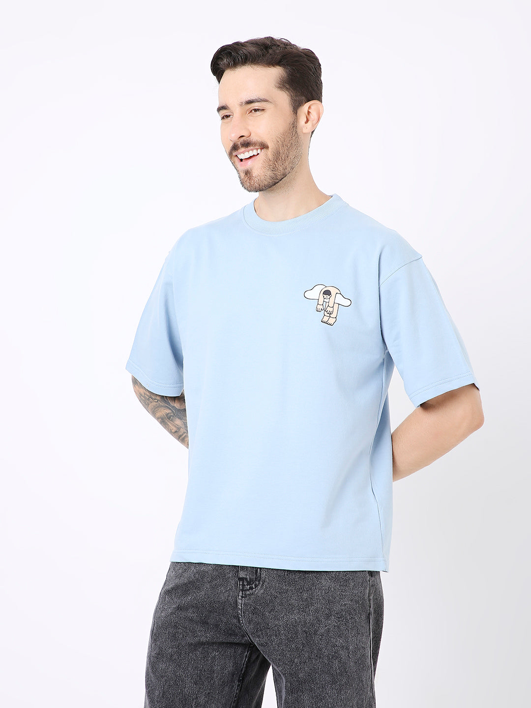 Light blue oversized T-shirt with small graphic print on the left chest, worn with dark jeans.