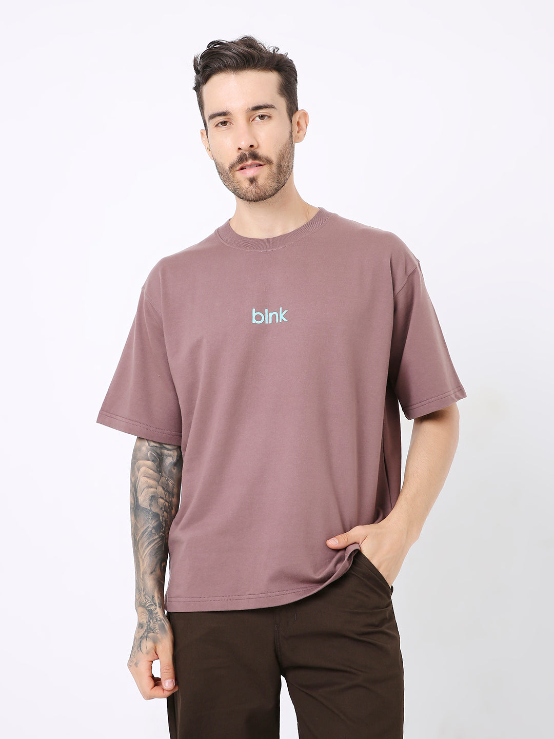 Oversize old rose T-shirt with blue "bink" text on chest, worn with dark brown pants.