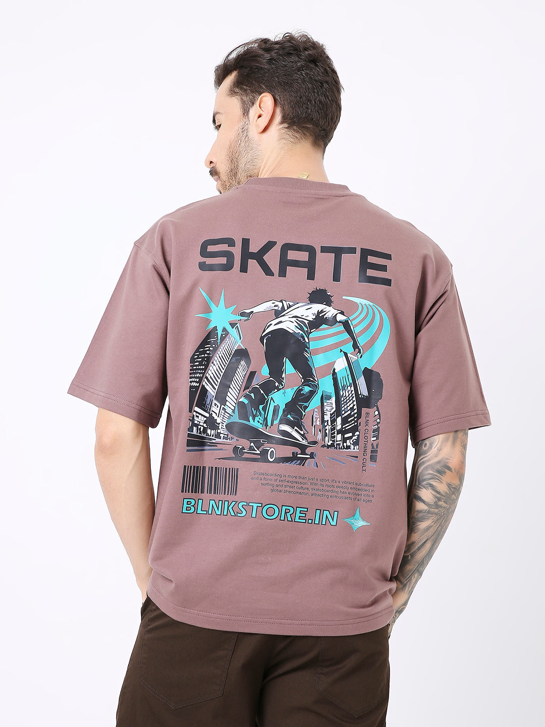 Oversize old rose t-shirt with black and blue skateboarding graphic and "SKATE" text on back.