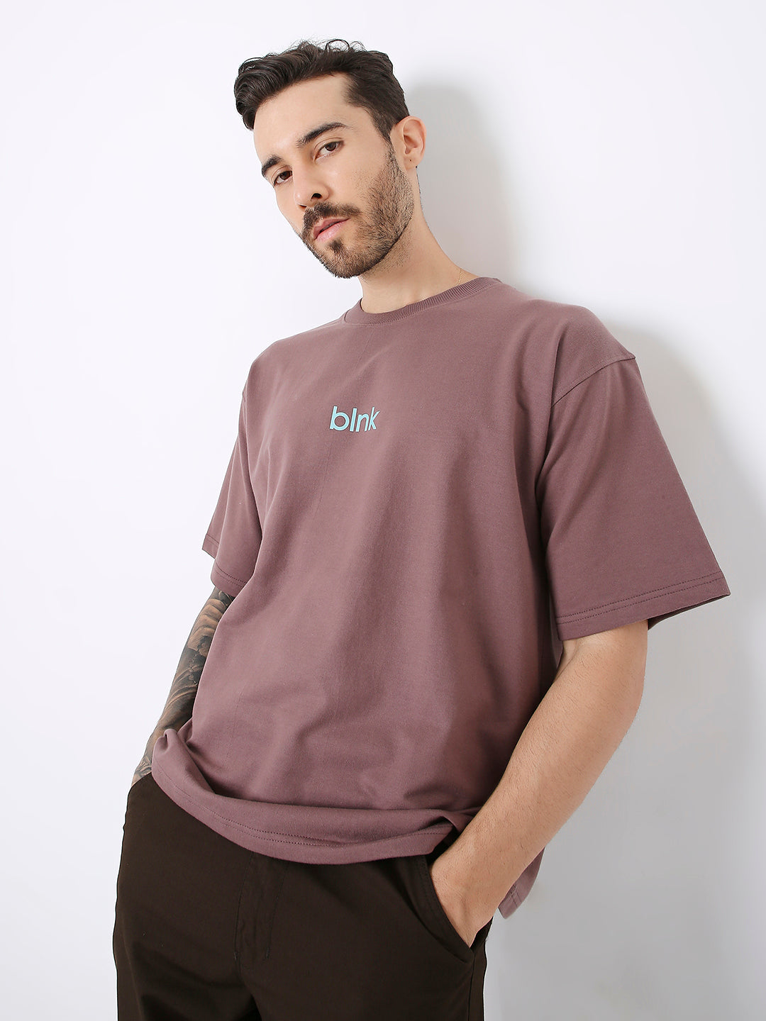 Oversize old rose t-shirt with light blue text logo, worn with black pants.