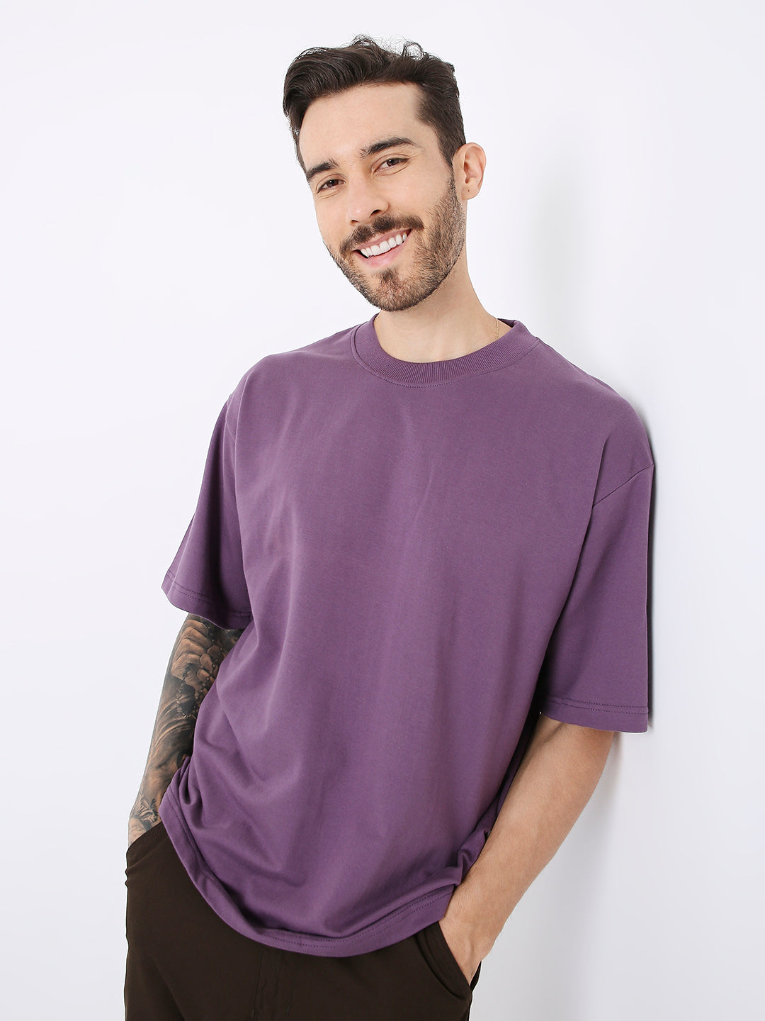 Oversize purple crewneck t-shirt with short sleeves on a smiling male model.