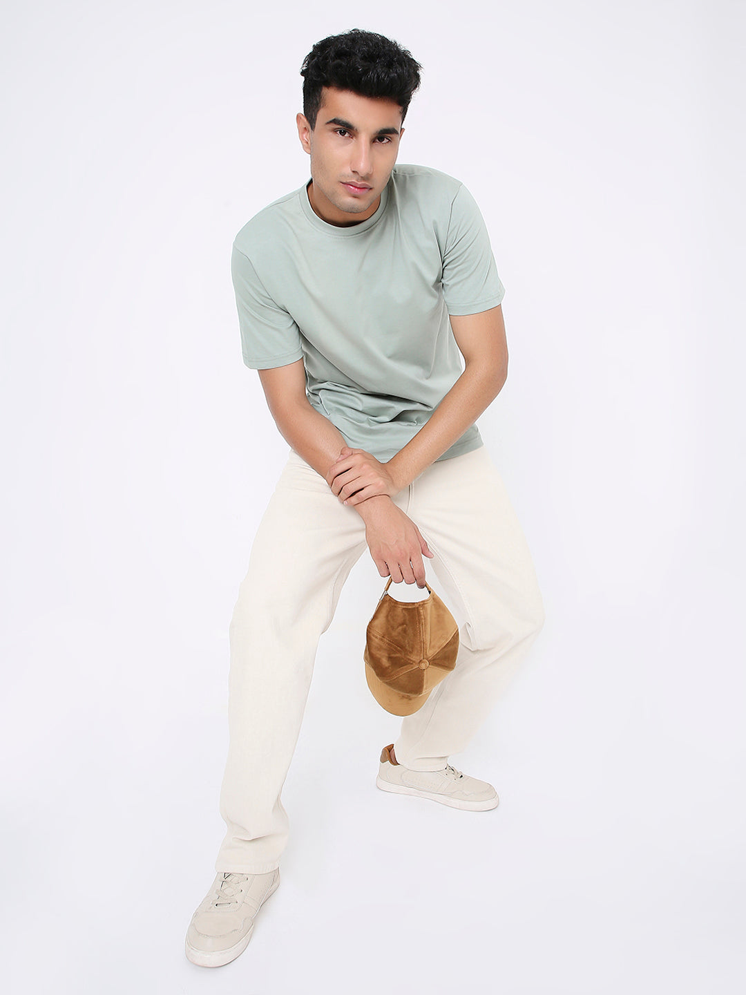 Relaxed fit sage green short-sleeve t-shirt on male model paired with cream pants and beige sneakers.