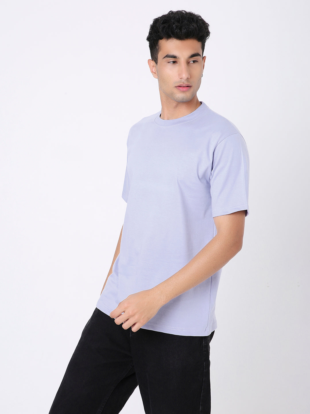 Man wearing relaxed fit lavender solid t-shirt with crew neck and short sleeves paired with black pants.