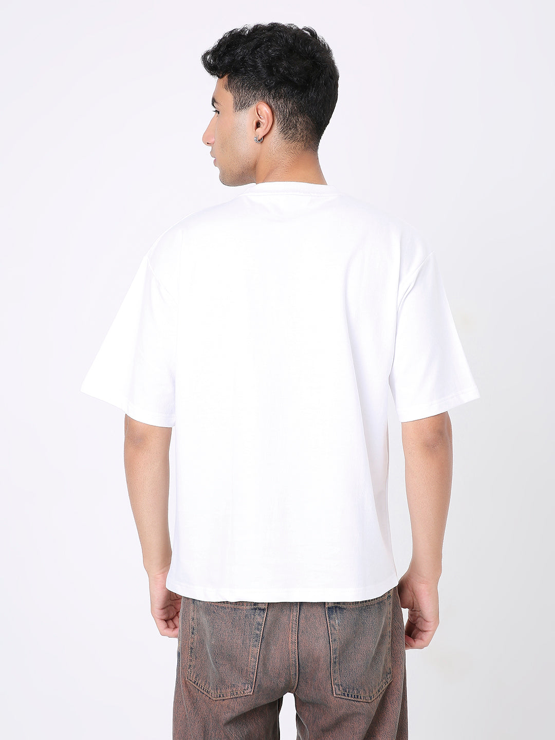 Oversize white solid t-shirt with short sleeves, worn untucked with casual brown pants.