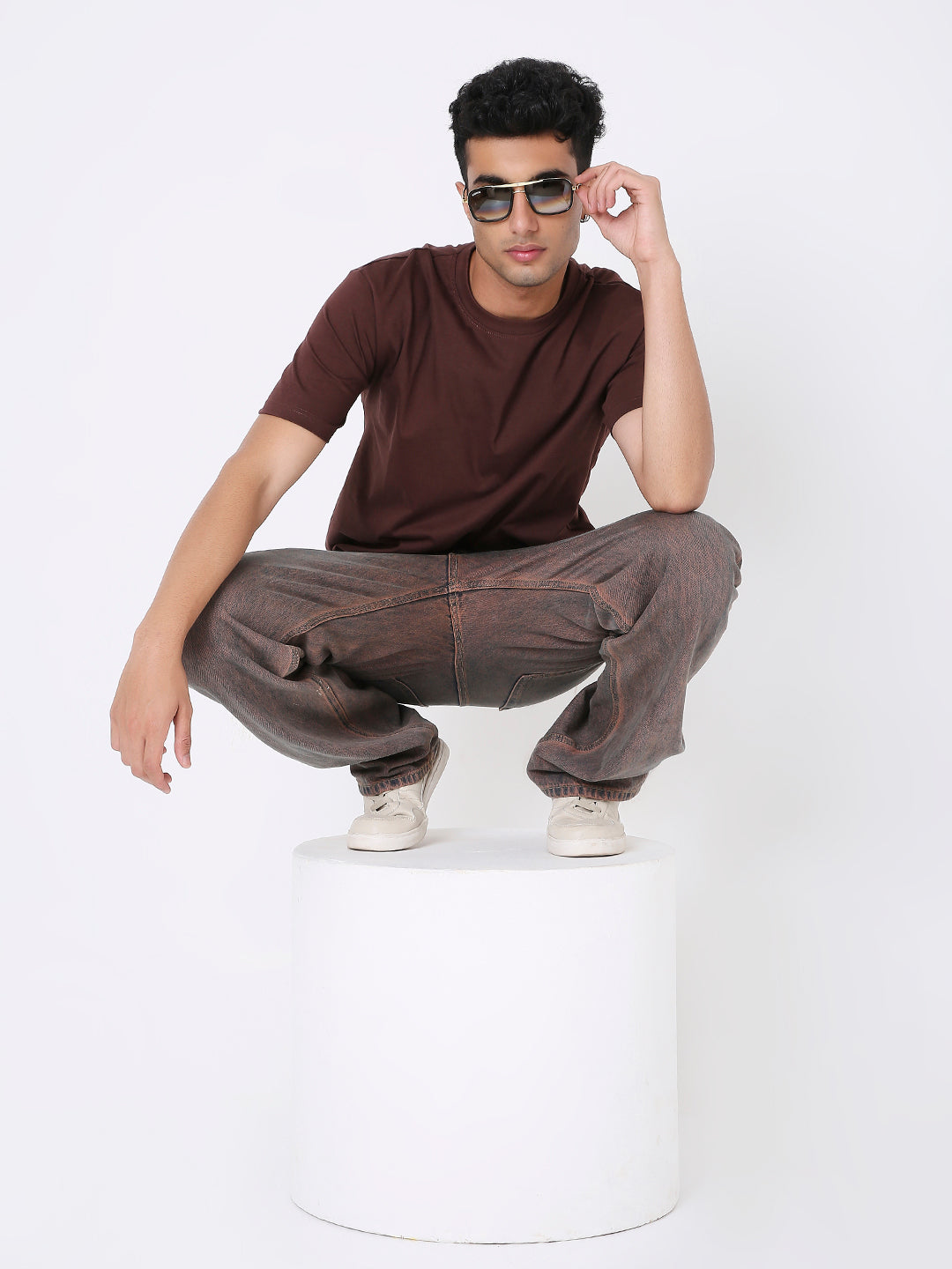 Brown relaxed-fit crew neck T-shirt worn with brown pants and white sneakers on male model with sunglasses.