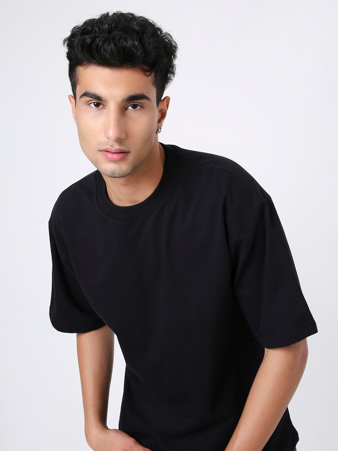 Oversize black solid short-sleeve T-shirt with relaxed fit on male model.