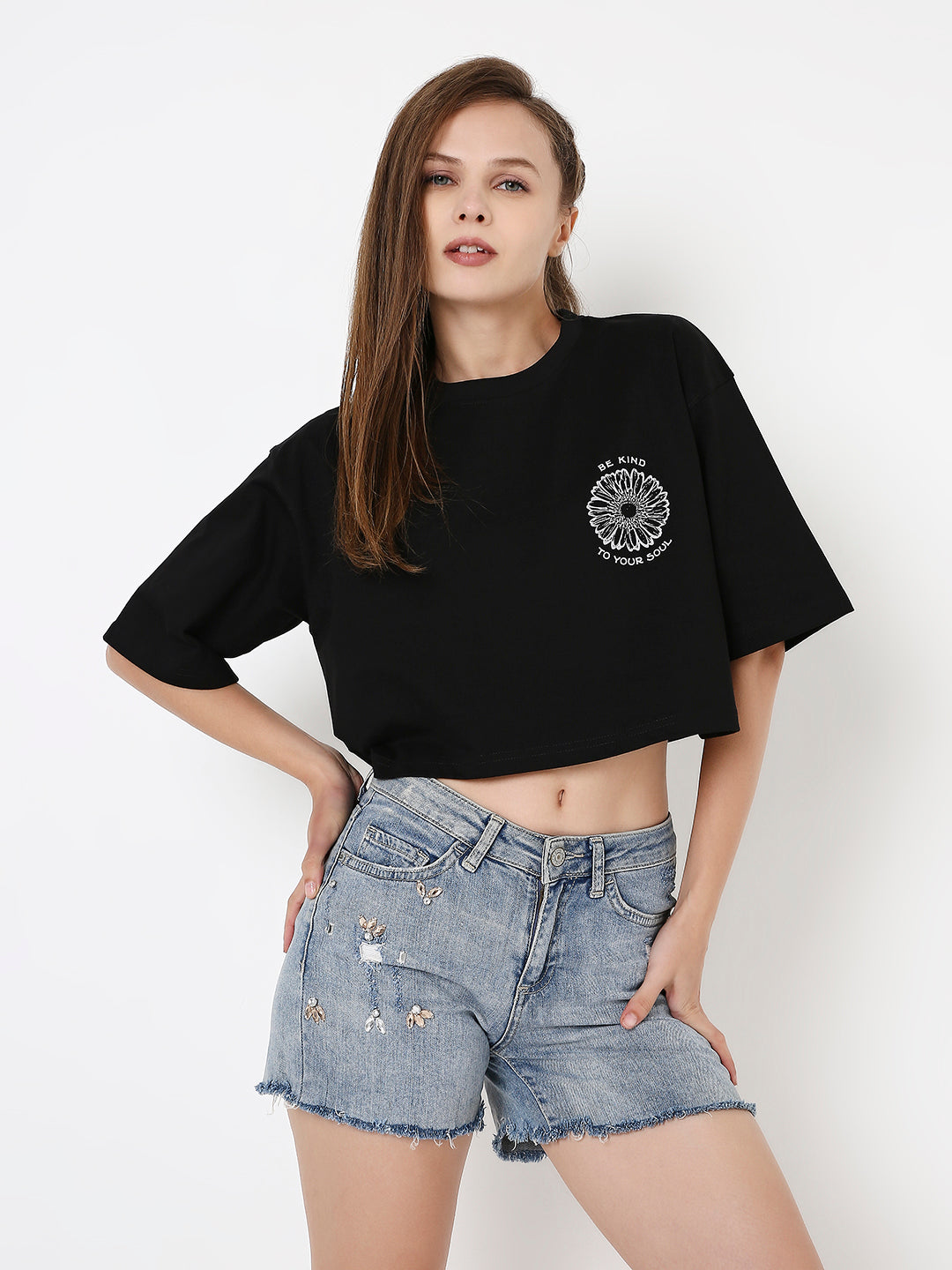 Oversize black crop top with white circular graphic on chest, paired with distressed denim shorts.