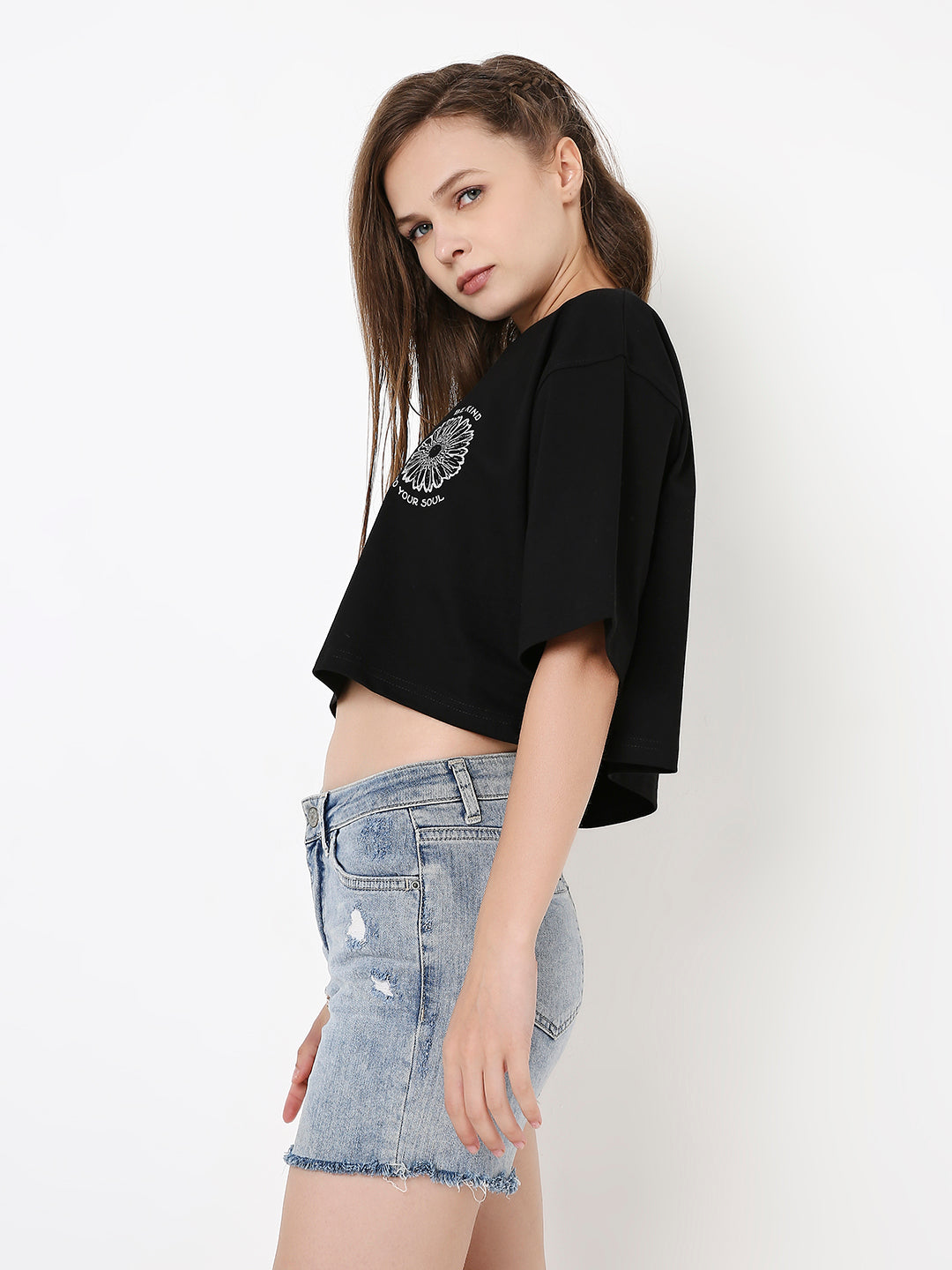 Black oversized crop top with white circular graphic print, paired with light blue distressed denim shorts.