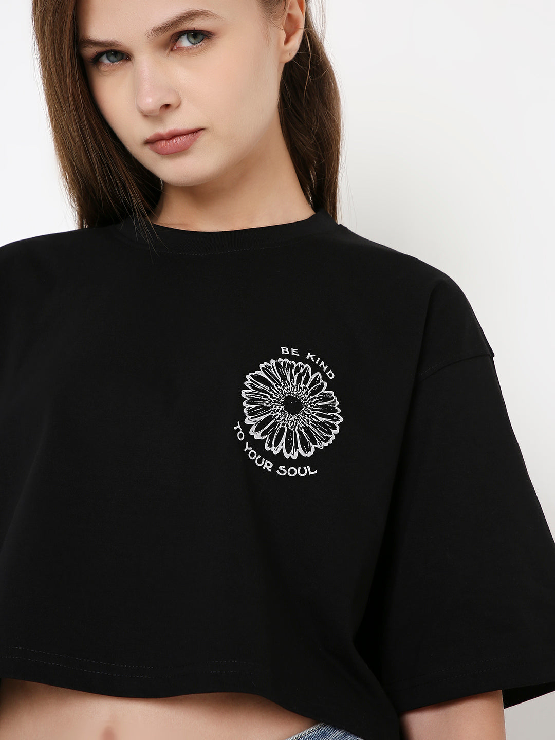 Oversize black crop top with white daisy graphic and text on chest, short sleeves.