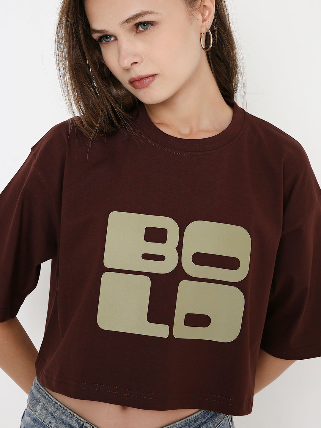 Oversize brown crop top with bold tan block lettering and short sleeves.