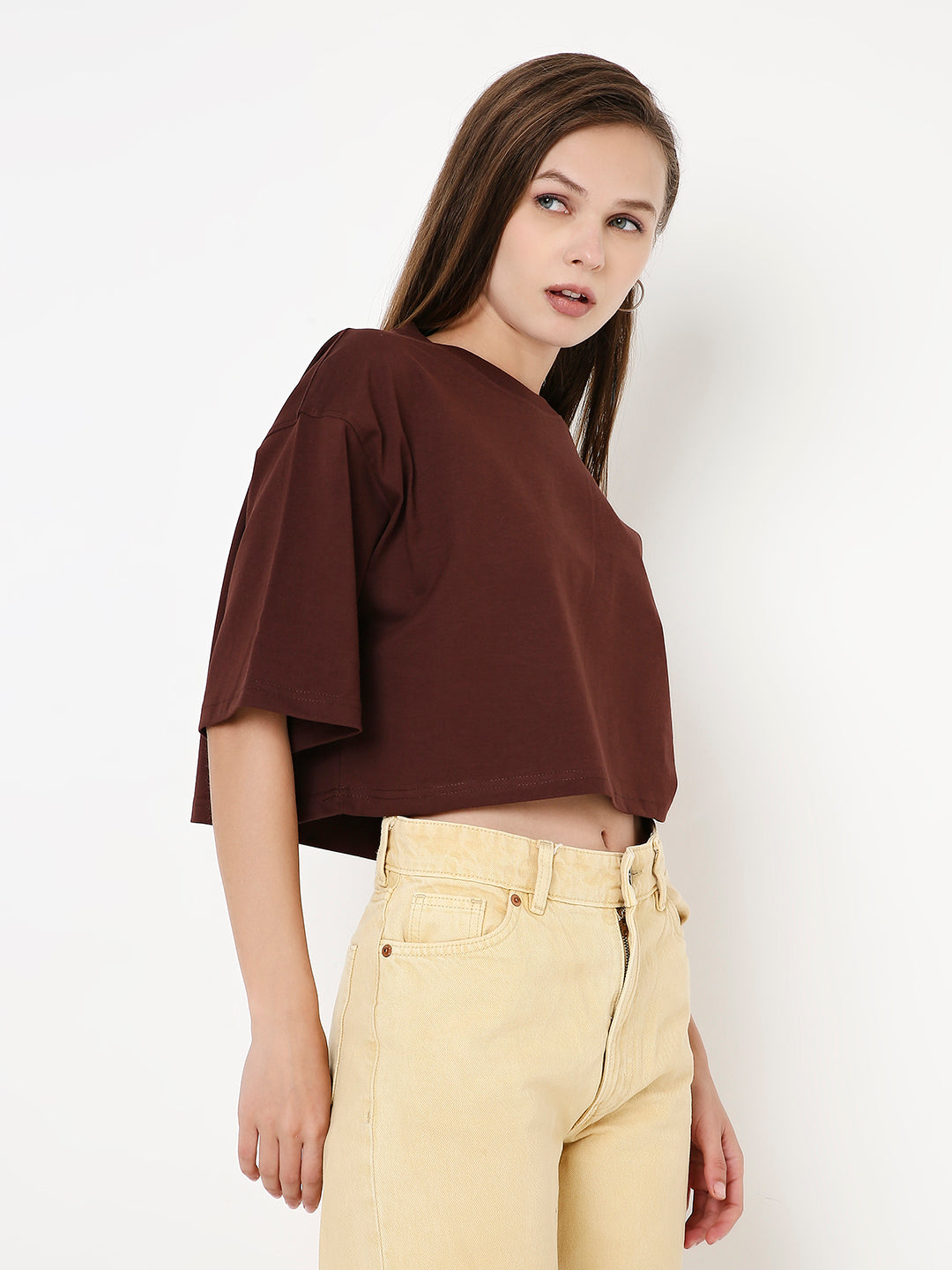 Oversize brown crop top with wide sleeves paired with high-waisted beige pants.