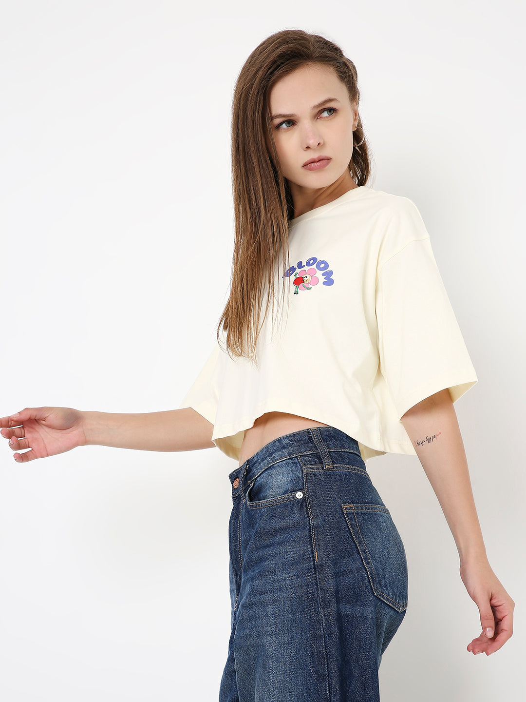 Off-white oversized crop top with colorful front graphic and short loose sleeves.