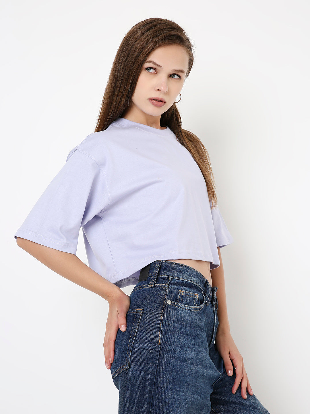Lavender oversized crop top with short sleeves and high neckline paired with dark blue denim jeans.