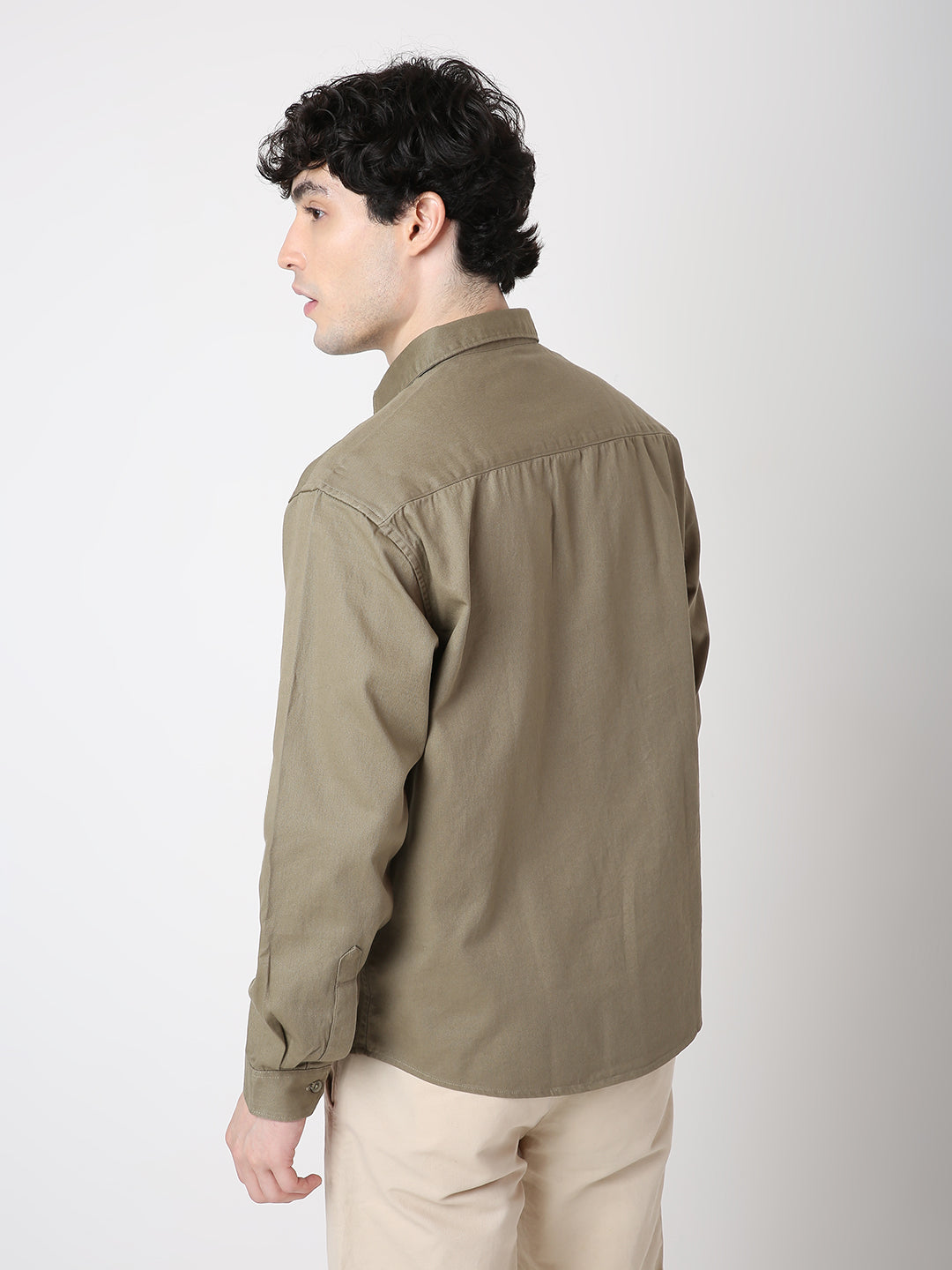Man wearing a green shirt and beige pants on a white background