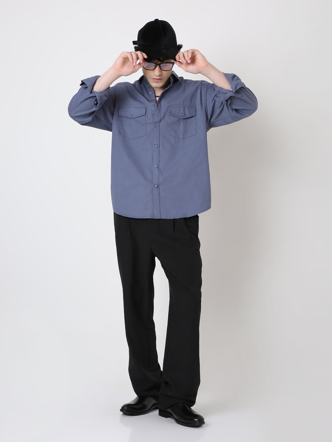 Person wearing a blue shirt and black pants with a white background
