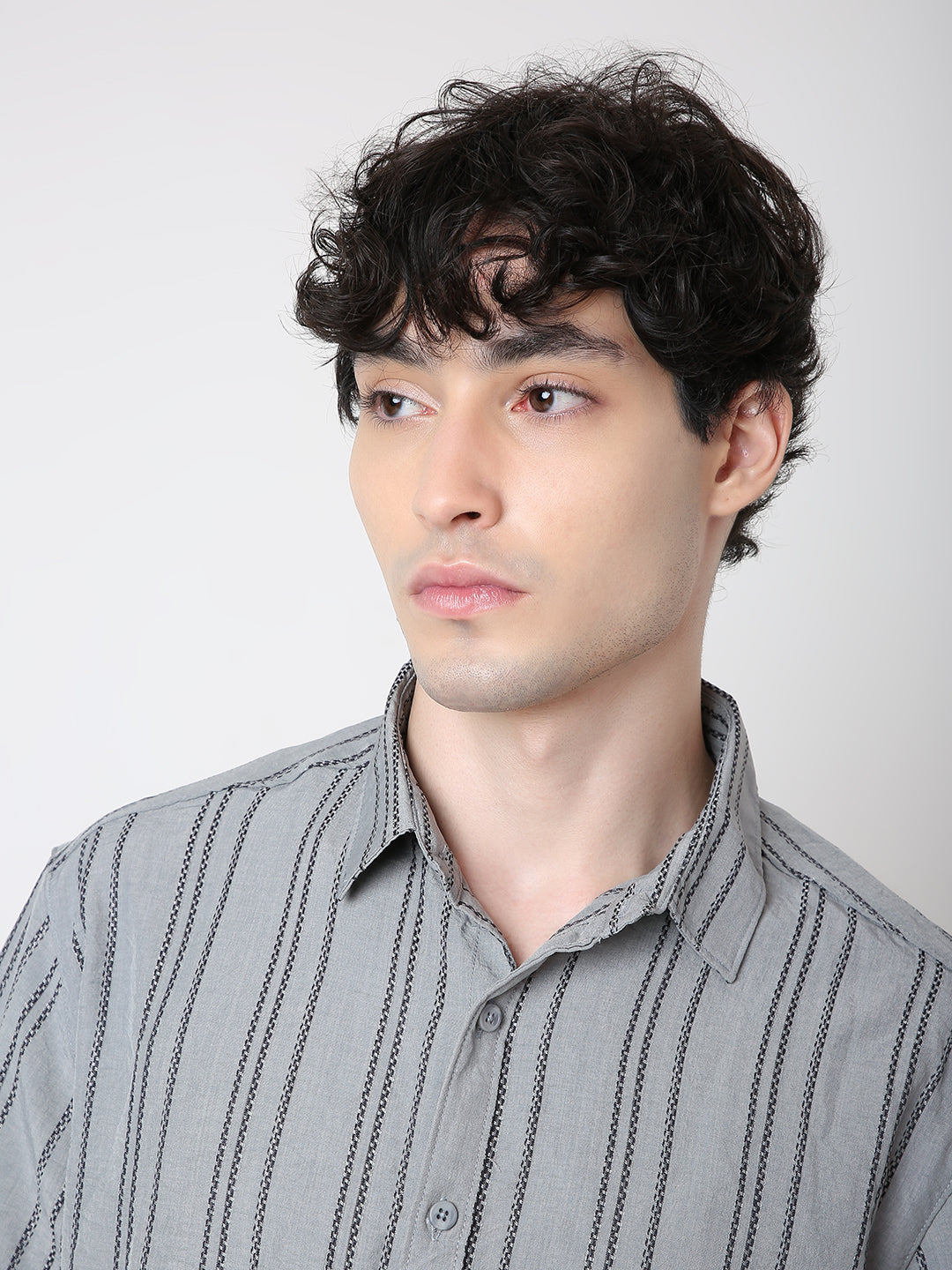Man wearing a gray striped shirt against a plain background