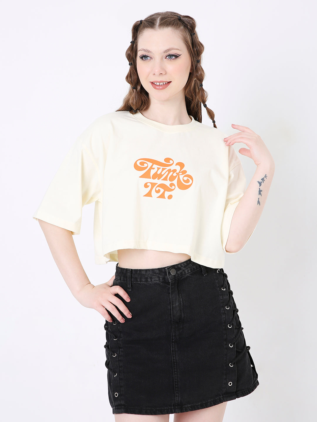 Off-white oversized crop top with orange graphic print paired with black button-up denim skirt.