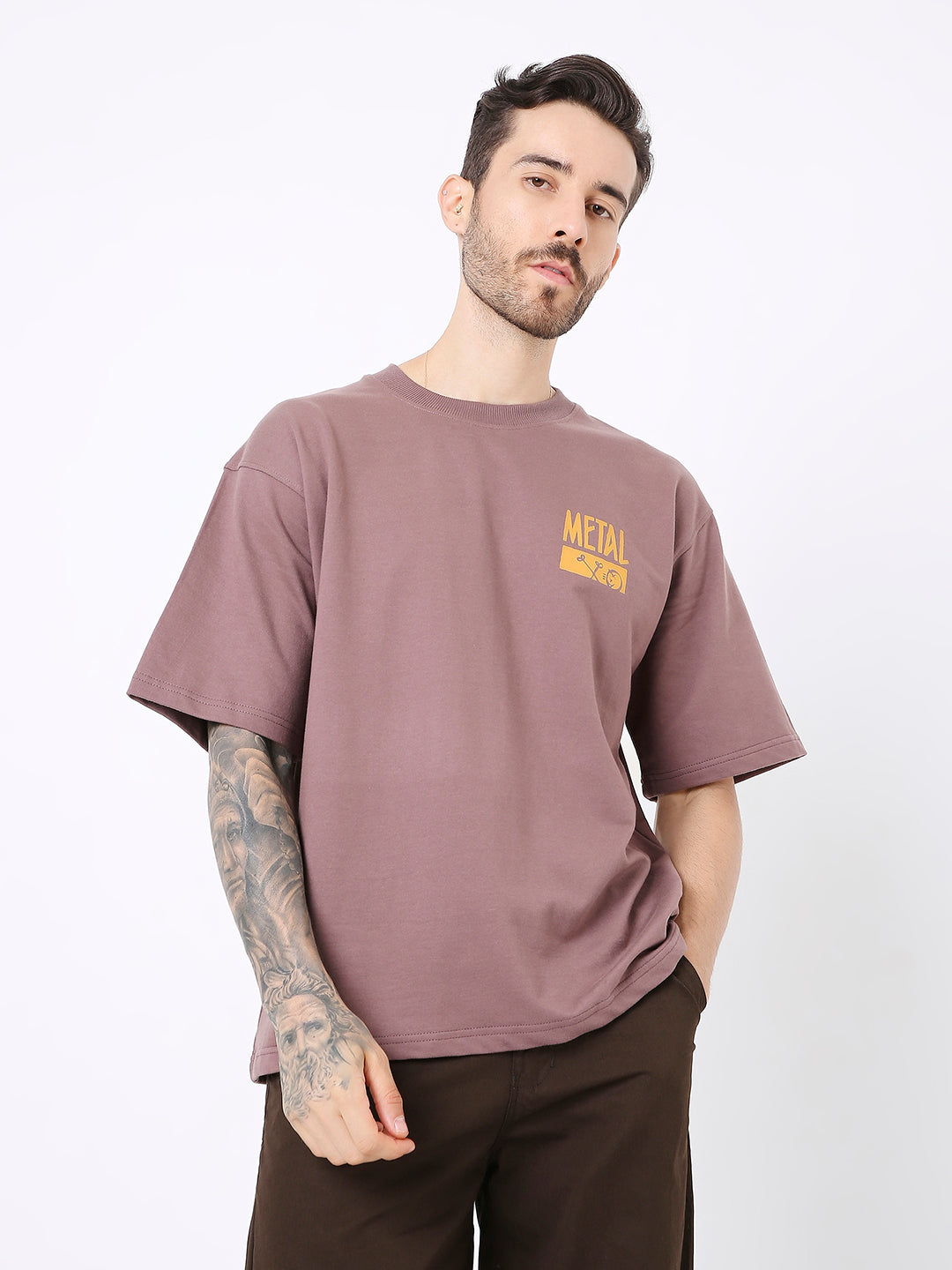Oversize old rose t-shirt with small yellow text print on left chest, worn with dark pants.