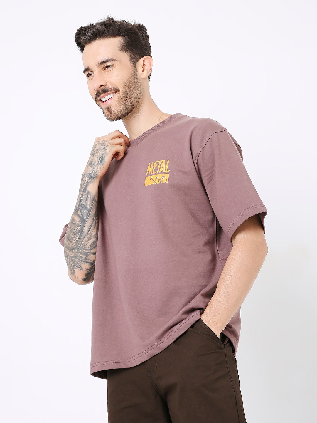 Oversize old rose t-shirt with small yellow graphic text on chest, styled with dark pants.